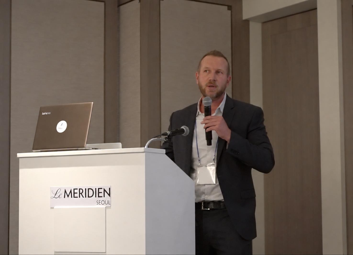 Neil Valentine speaking at a podium in Seoul